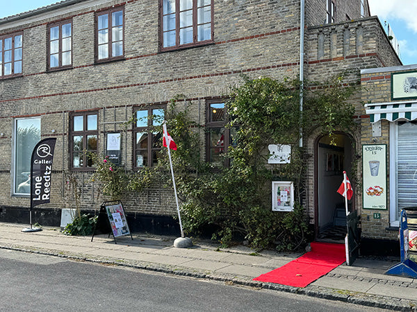 Dragør Havnegalleri udefra med rød løber samt beachflag og skilte om Lone Reedtz